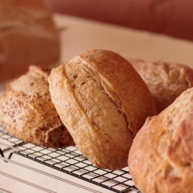 Close-up of fresh artisan bread loaves cooling on a wire rack in a bakery.