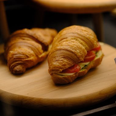 Tasty croissants with fresh vegetable fillings displayed on wooden trays.